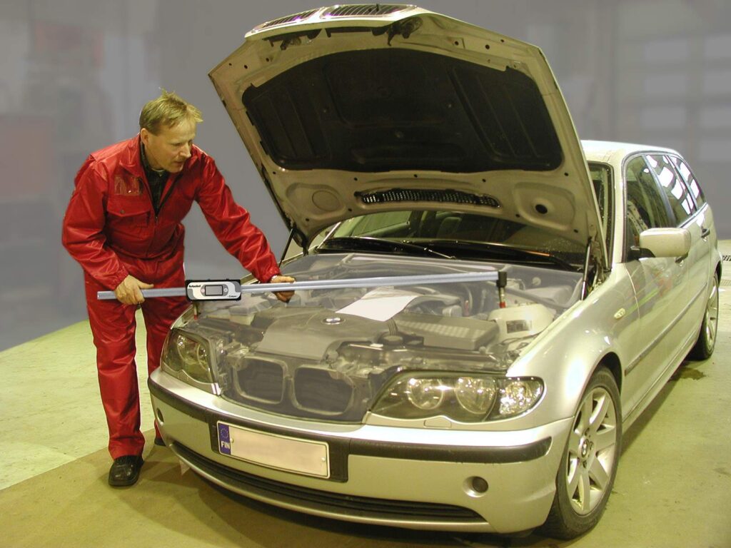 A man measuring the car’s engine compartment area.